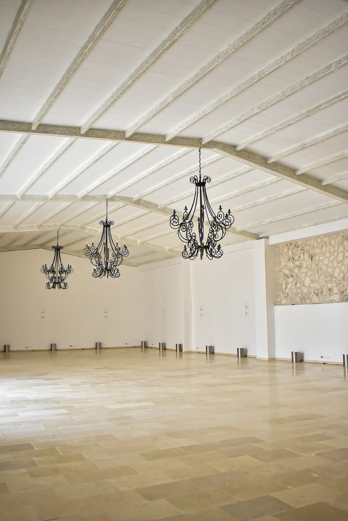 Salón de Casa Real con muros claros, vigas y lámparas ornamentales
